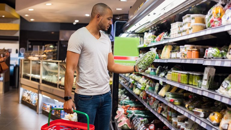 person_selecting_a_bag_of_salad_mix_in_a_supermarket