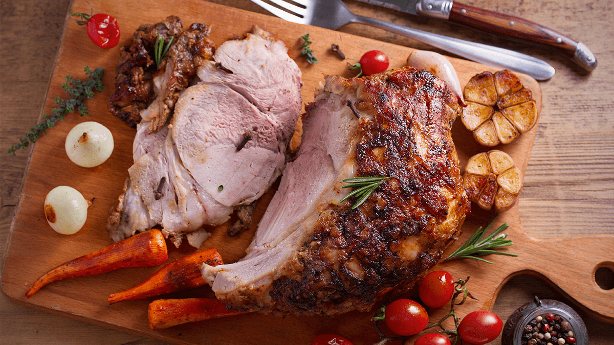 glazed christmas ham being sliced on a wooden board