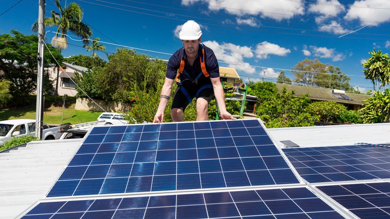 solar panel technician installing panel on australian home
