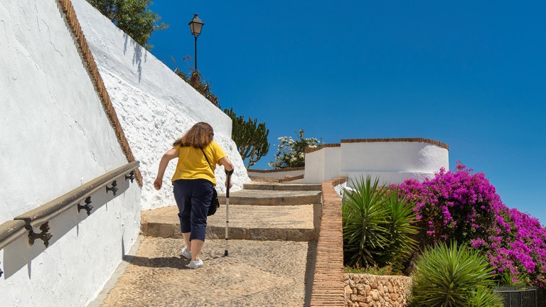 tourist using crutch to walk up steps in spain