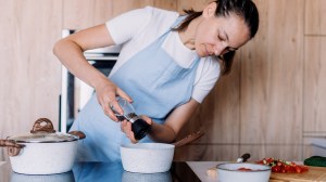 person adding pepper to a saucepan on an induction cooktop