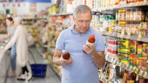 senior person comparing products in supermarket