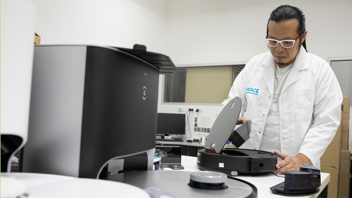 CHOICE tester Matthew Tung checking dust canister in a robot vacuum