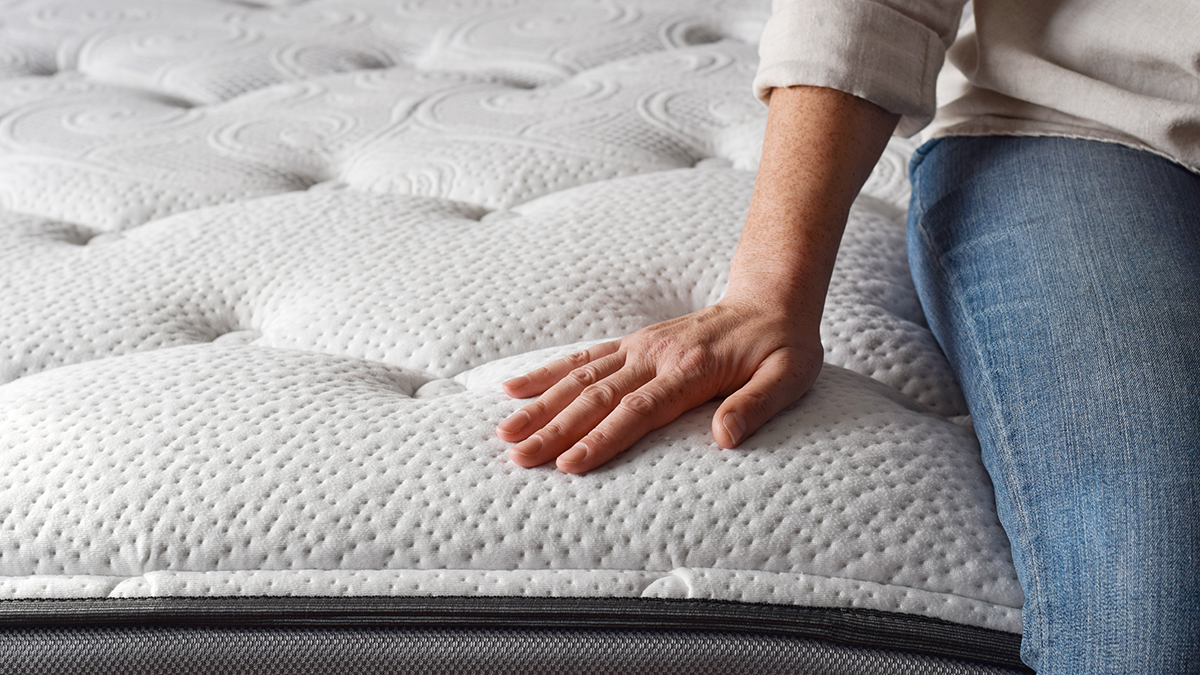 closeup of person sitting on mattress and testing support