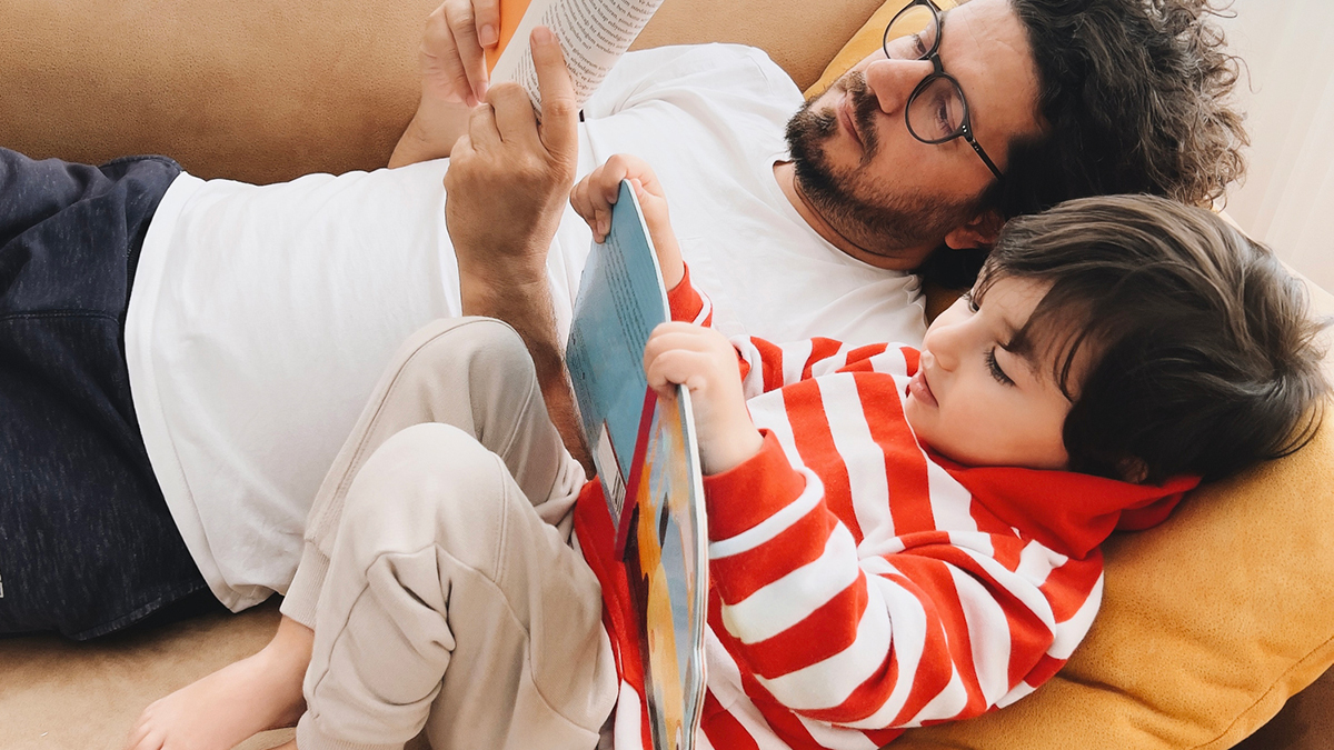 father_and_son_reading_library_books_on_sofa