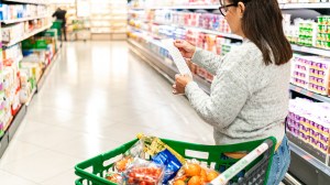 woman in grocery store with trolley checking prices