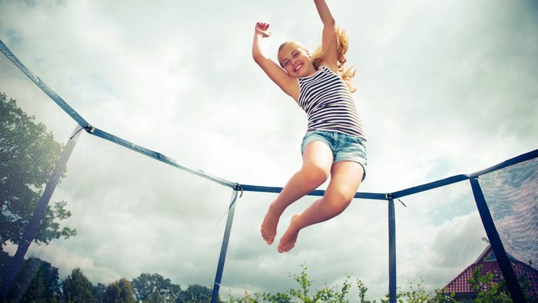 child jumping on trampoline in backyard