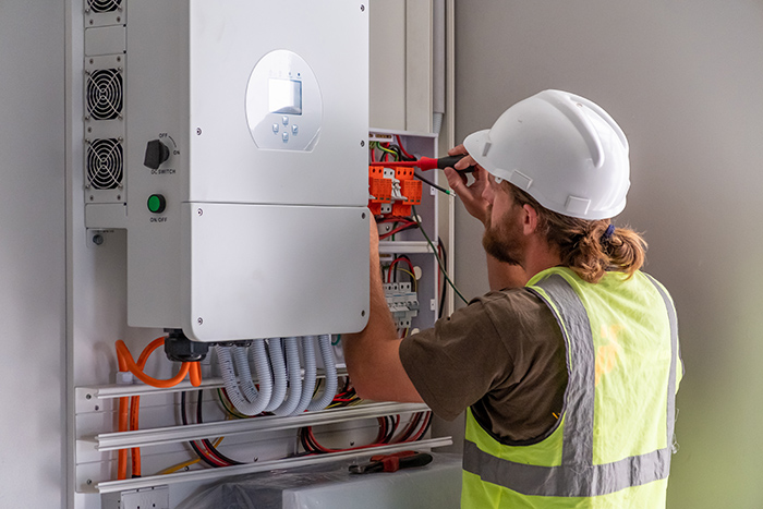 Electrician installing a solar energy inverter