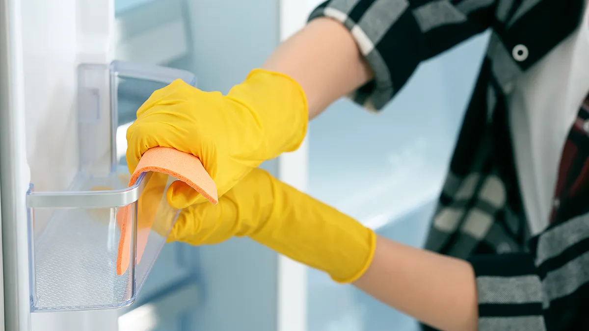 person cleaning the shelves inside a fridge door