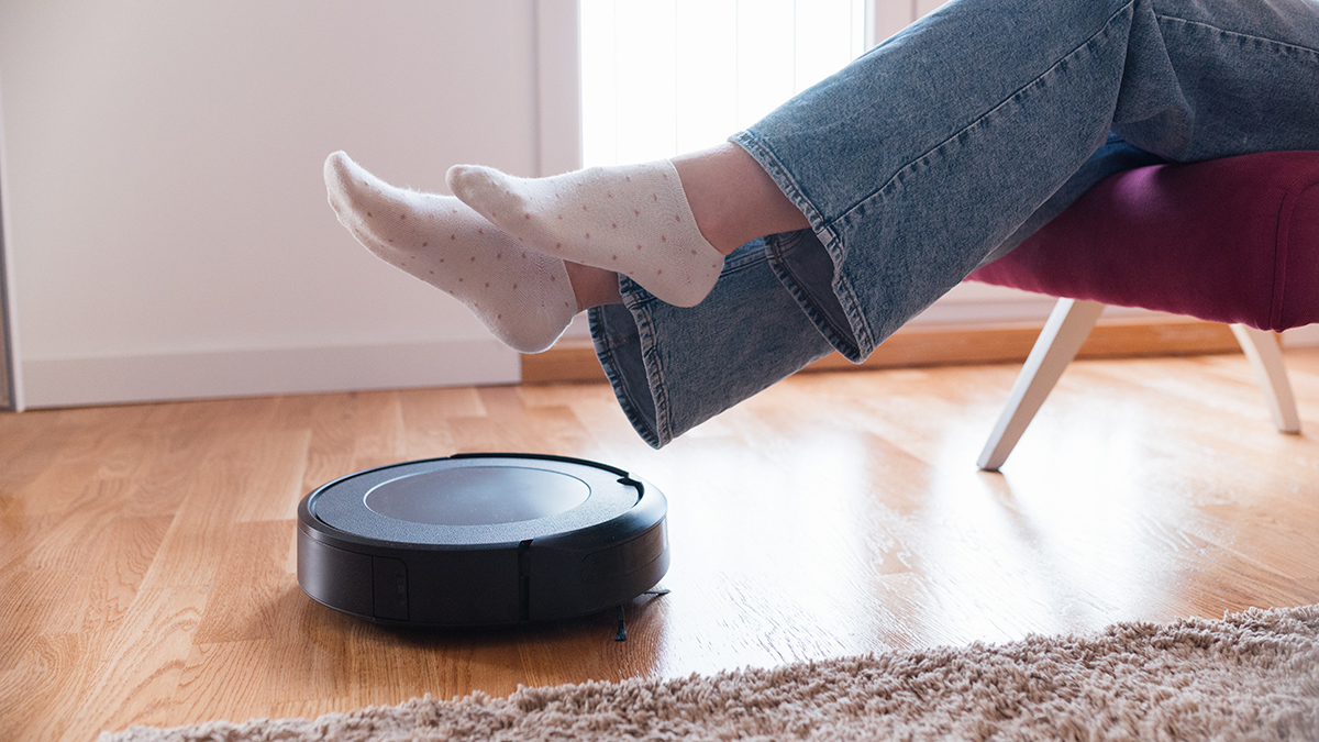 Person lifting their feet as a robot vac cleans underneath