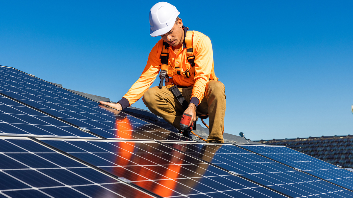 Person installing solar panels in a roof on a house
