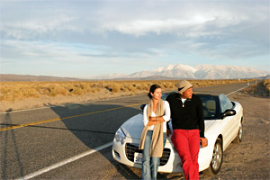 couple leaning on a car by the side of the road